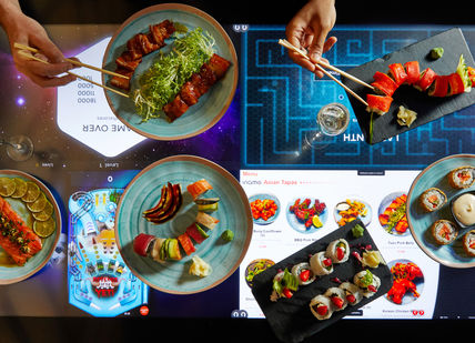 An image of a table with plates of food, Comedy Night and Dinner. inamo Restaurants