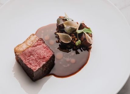 A piece of steak on a plate with sauce.