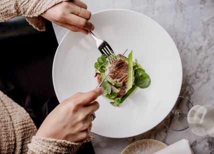 A person eating a plate of food with a fork.