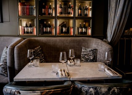 An image of Two glasses of wine on a table next to a plate of food at the La Bibliotheque