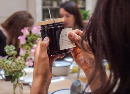 A person putting a label on a camdle.