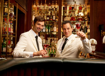 An image of two men with glass of whisky at the bar