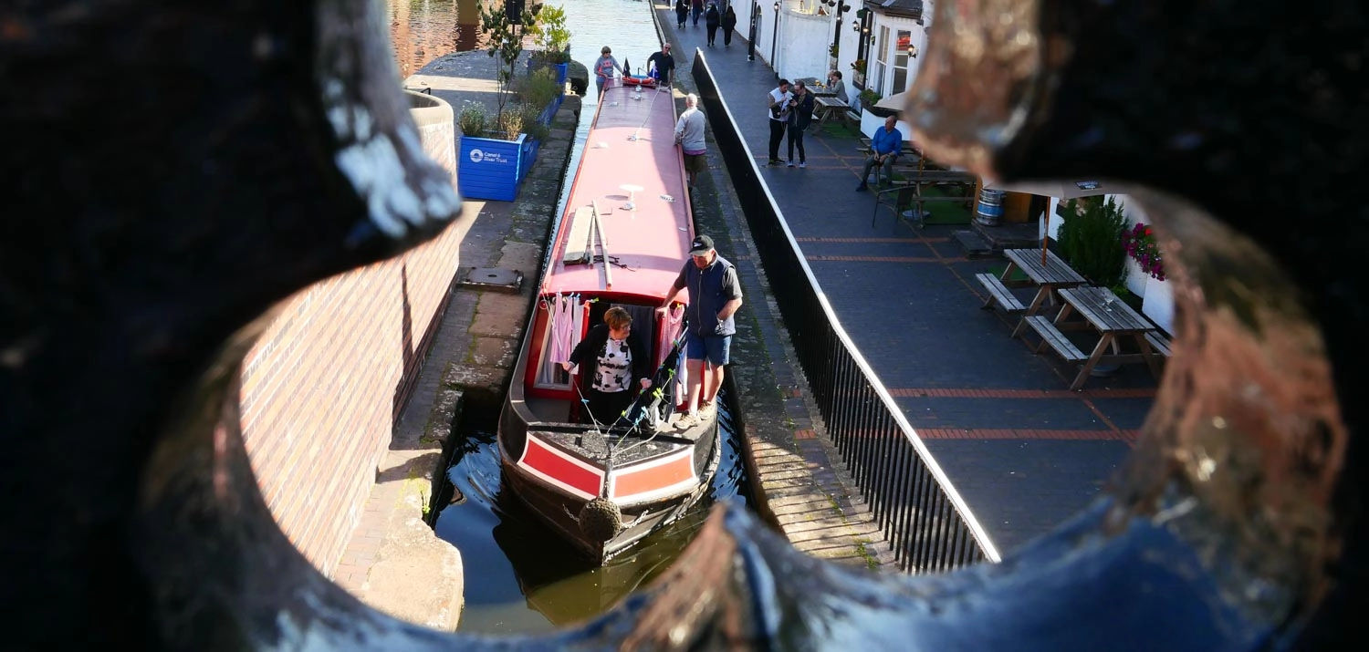 A canal boat is seen through a hole in a wall.