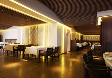 An image of a restaurant setting with tables and chairs, Six-Course Seafood Tasting Menu. Quilon