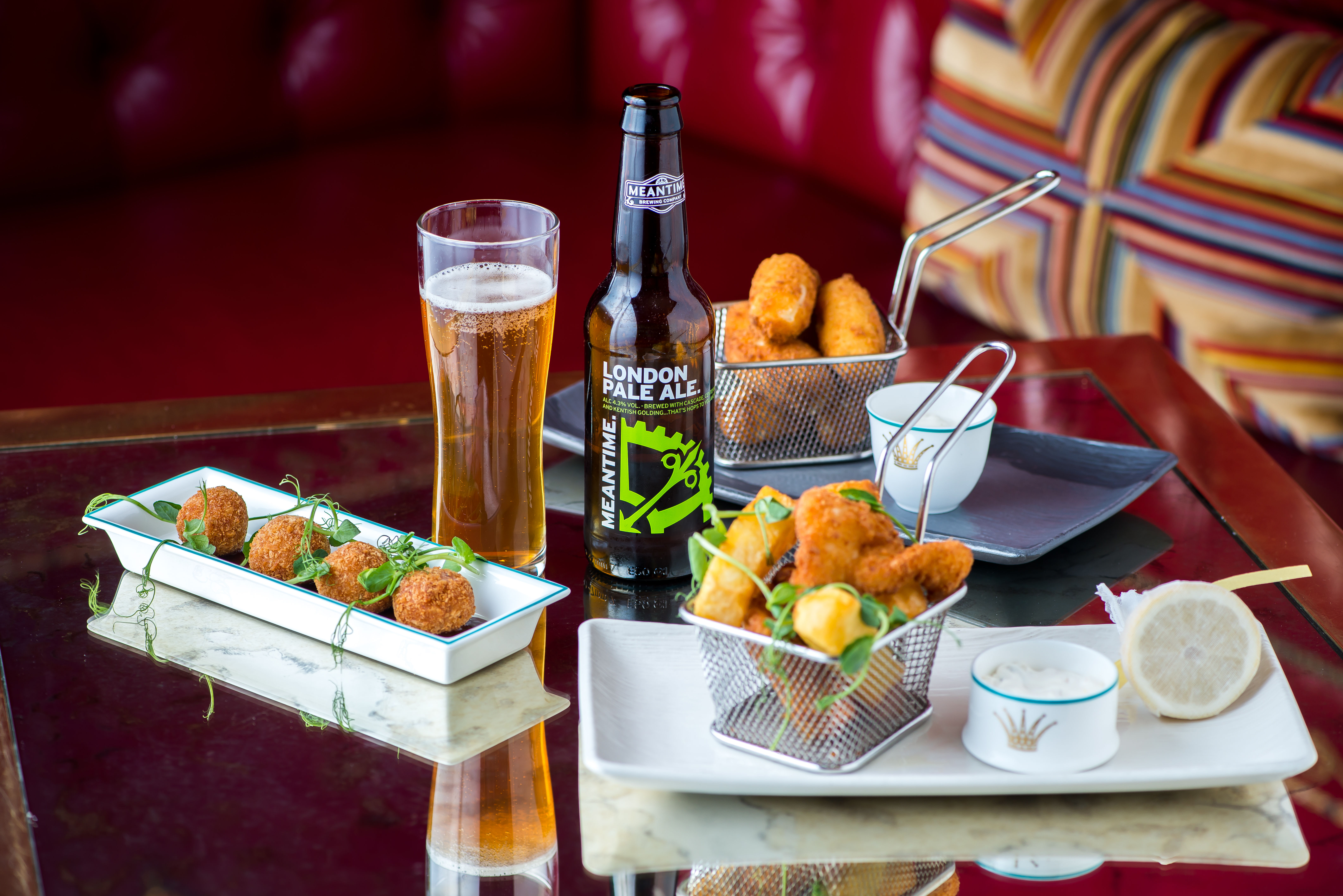 A glass of beer on a table next to a plate of food.