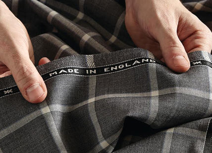 An image of a man's hands tying a tie, Create a Bespoke Two-Piece Suit. Stowers London