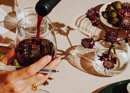 An image of a table with a person holding a wine glass, Three-Month Virtual Wine Course. The Wine List