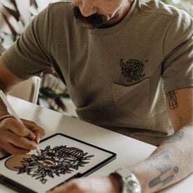 fit model sketching on his tablet in The Heavy Bag Tee in Sage Dahlia