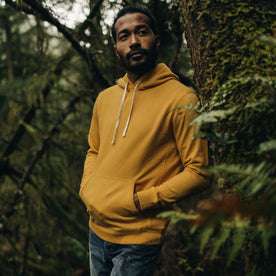 fit model leaning against a tree in The Fillmore Hoodie in Canary