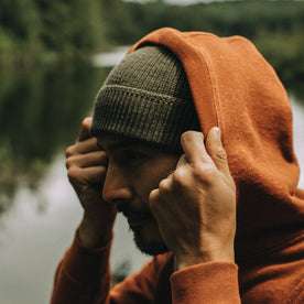 fit model wearing The Rib Beanie in Heather Forest under his hoodie