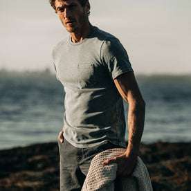 fit model wearing The Heavy Bag Tee in Sea Green, standing on coast