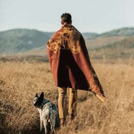 Fit model wearing The Golden State Blanket in Rust in a field with his dog