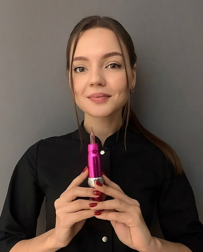 Permanent Make-up Artistin Anna Tashlieva mit Pigmentiergerät in der Hand, lächelt freundlich in die Kamera.