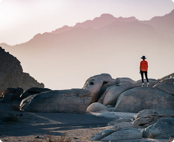 Person standing on rocks overlooking mountains