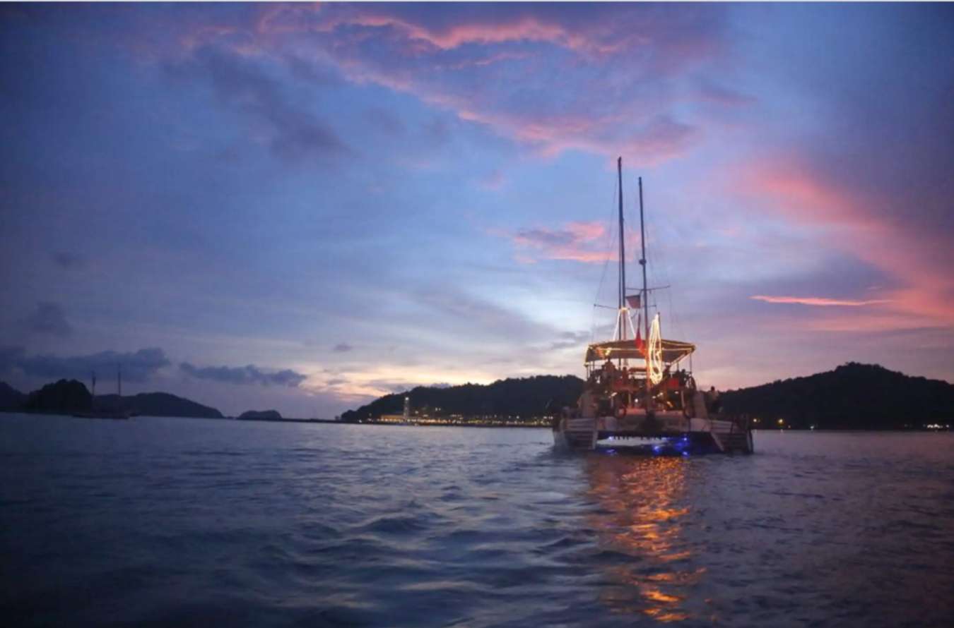 a catamaran boat cruising the ocean during dusk