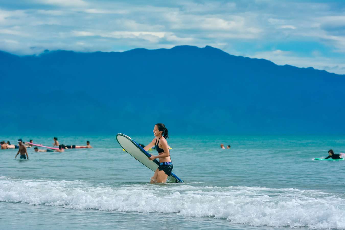 A woman holds a surfboard at popular surfing destination in Baler