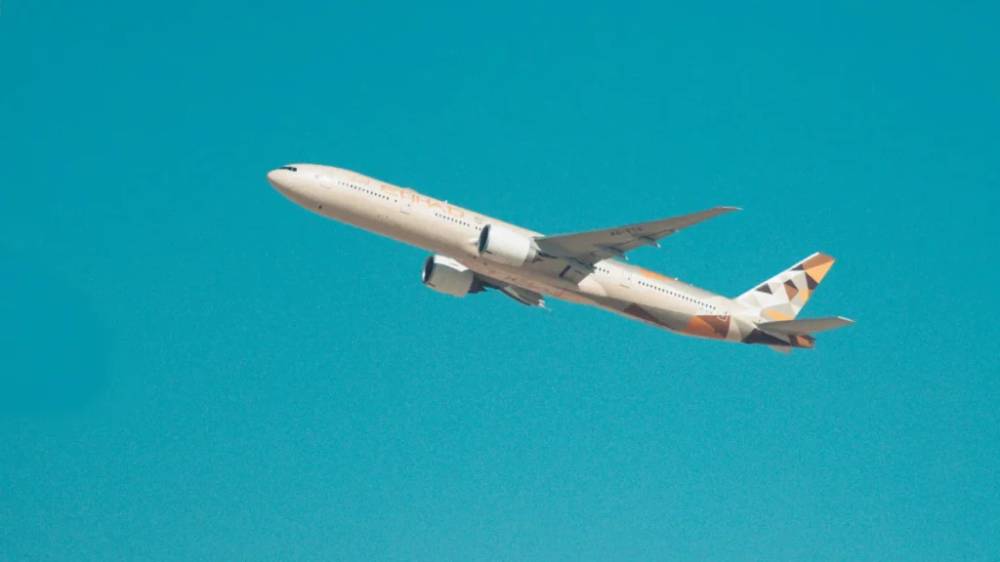 An Etihad plane against a clear-blue sky.
