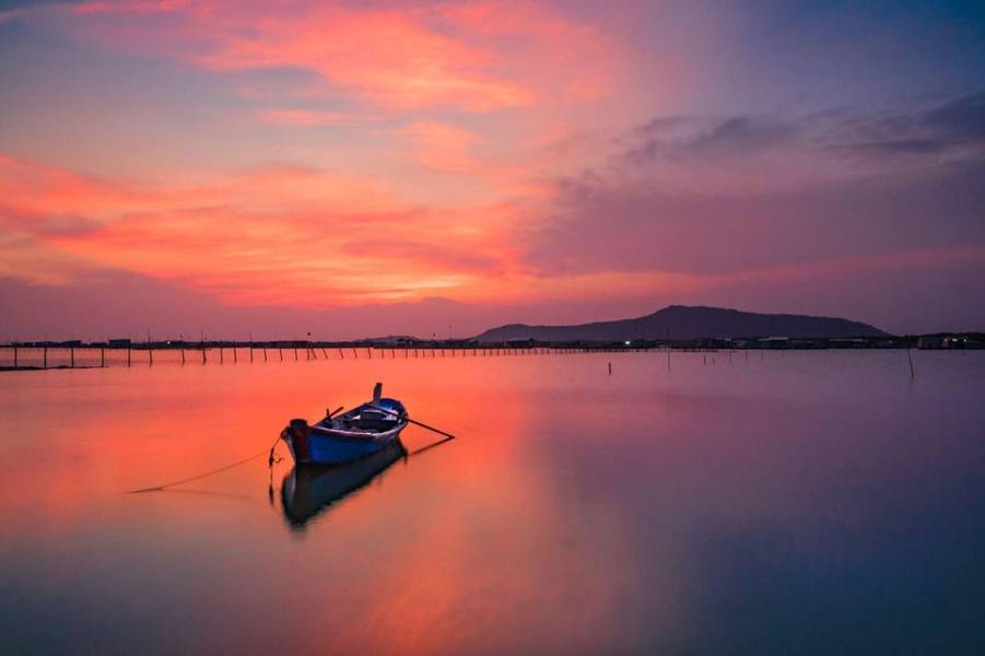 Khung cảnh hoàng hôn rực rỡ với sắc cam phản chiếu xuống mặt hồ yên ả tại đảo Long Sơn