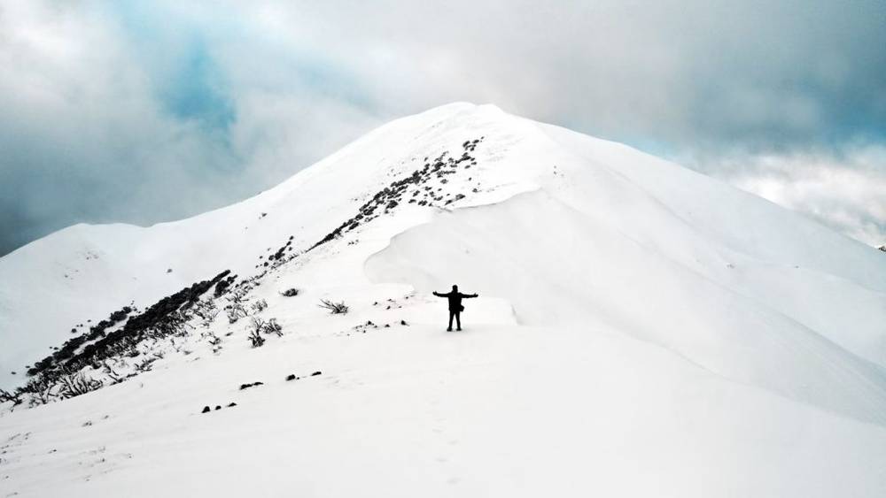 A person standing in the the snow on a mountain near Mount Hotham, Victoria.