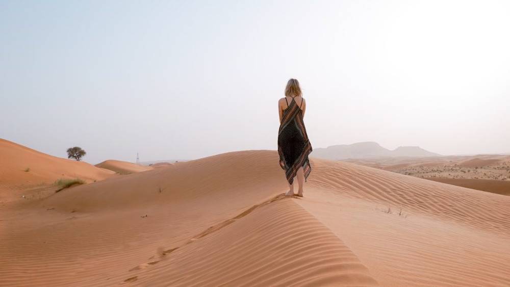 A woman standing on a sand dune in Dubai.