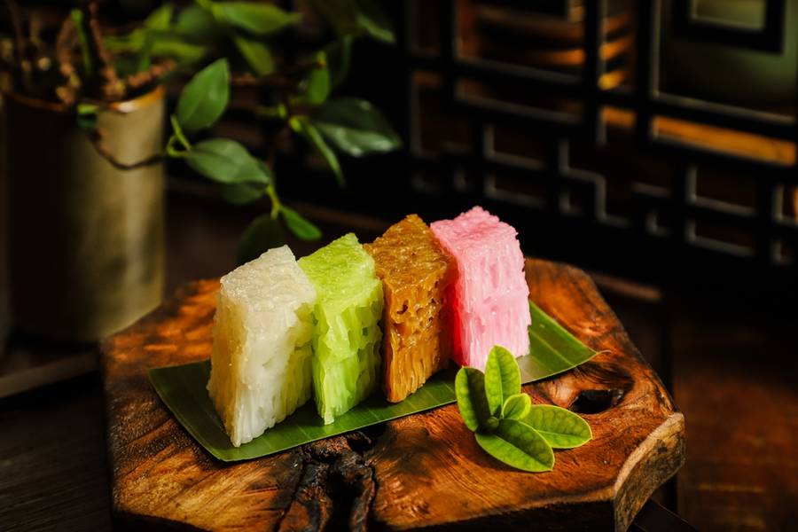 Bai Tang Gao. Chinese steamed rice cake, made into several flavors and colors. The slices are served on a rustic wooden block. 