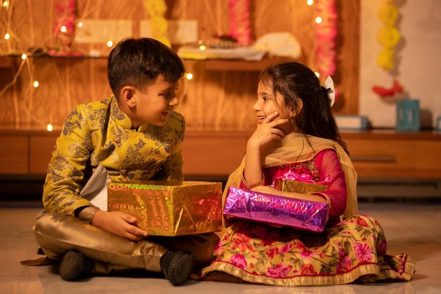 Happy little indian kids brother and sister holding gift boxes 