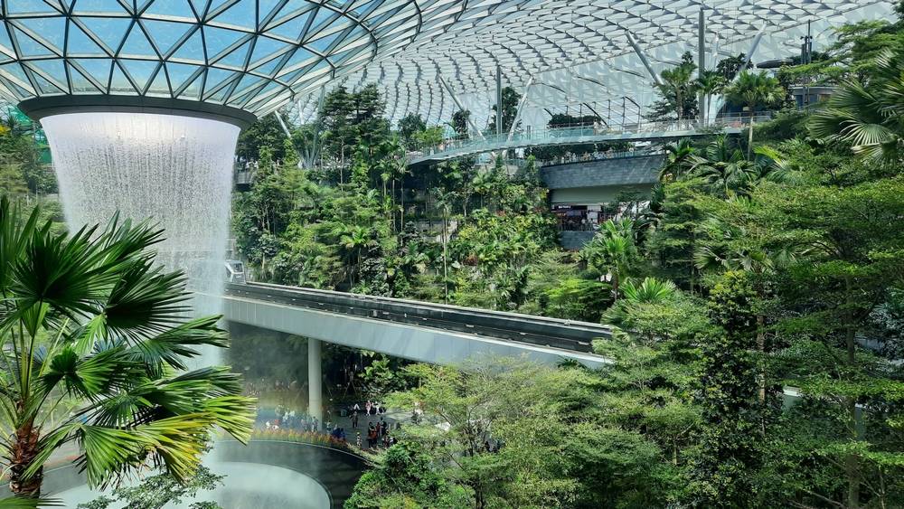Sky trains passing roof waterfall at "Jewel" area, Terminal 1, Changi airport, Singapore