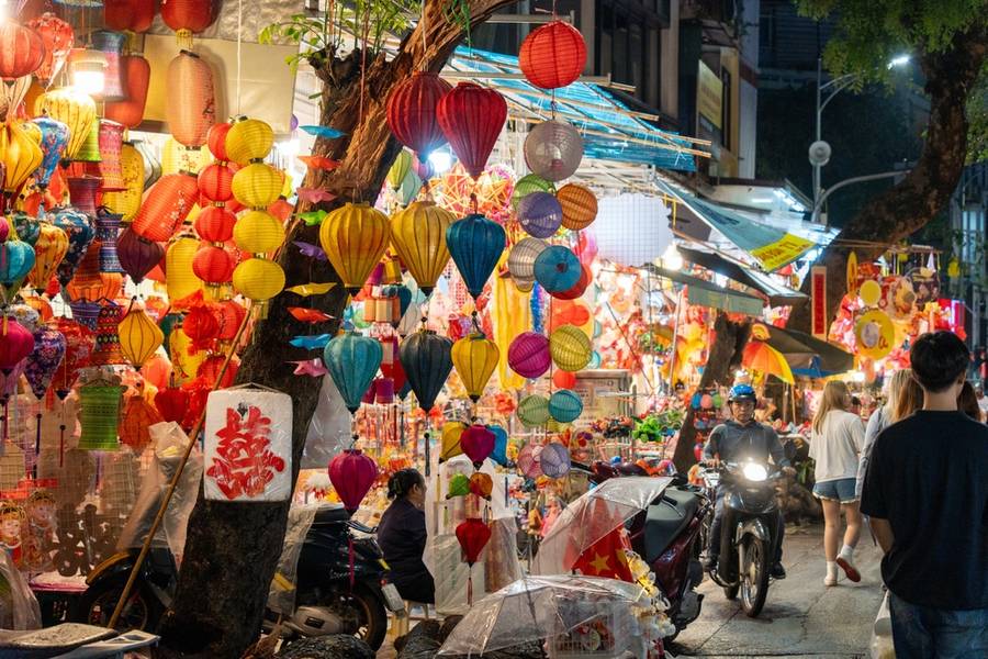 Hanoi city, Vietnam - 10 Sep 2024: People in front of traditional colorful lanterns hanging on a stand in Hang Ma street, Hanoi city, Vietnam during Mid Autumn Festival. Joyful and happy. 
