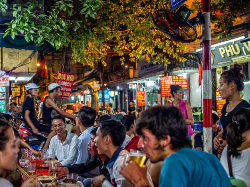 Locals and tourists drink freshly brewed beer in the streets of Hanoi
