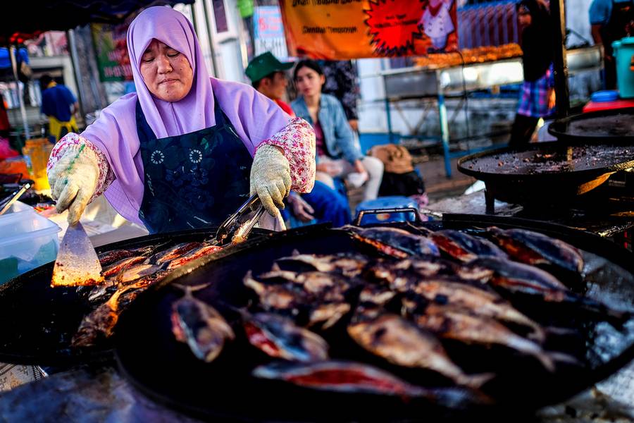SELANGOR, MALAYSIA - JUNE 30, 2014 : A woman seller prepares grill fish at Street market or known as 'Pasar Malam' in Petaling Jaya , Selangor