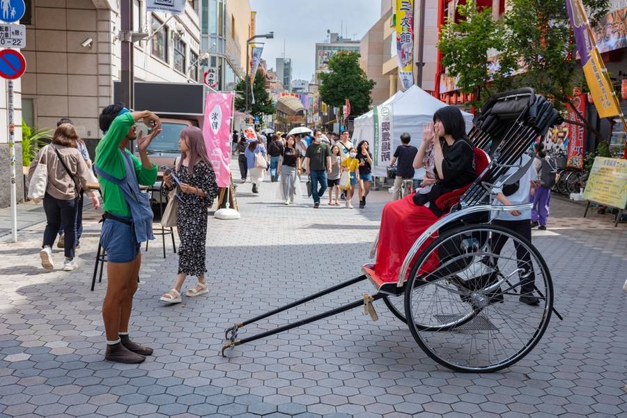 Tokyo, Japan - Jun 15, 2024: Tourist explore Nakamise, the most famous shopping street in Asakusa near the Senso-Ji Temple, Tokyo's oldest-established temple by arickshaw or jinrikisha.