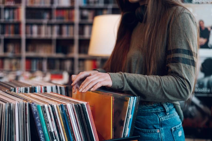 Close up of a woman hands choosing vinyl record in music record shop. Music addict concept. Old school classic concept. Focus on the hands and a vinyl record.
