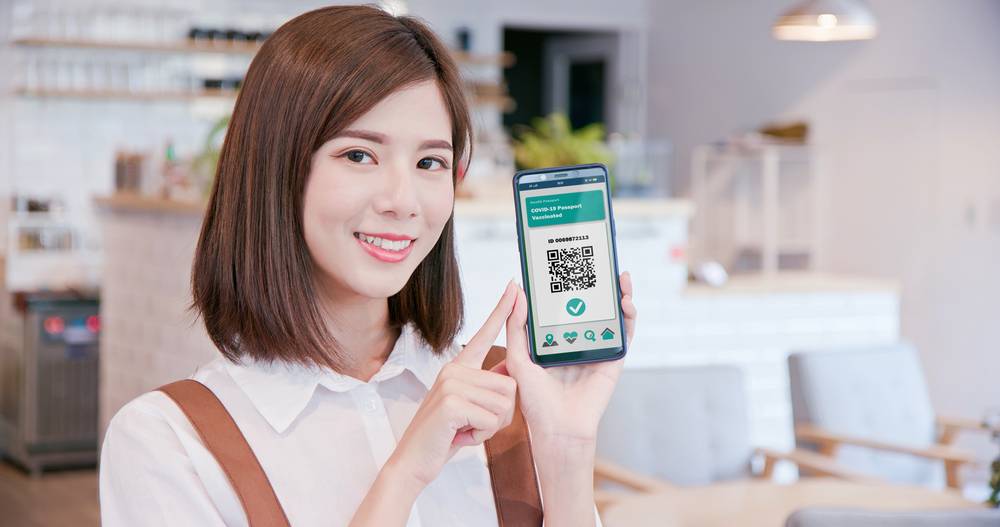 Asian woman holding cellphone with digital health e-passport
