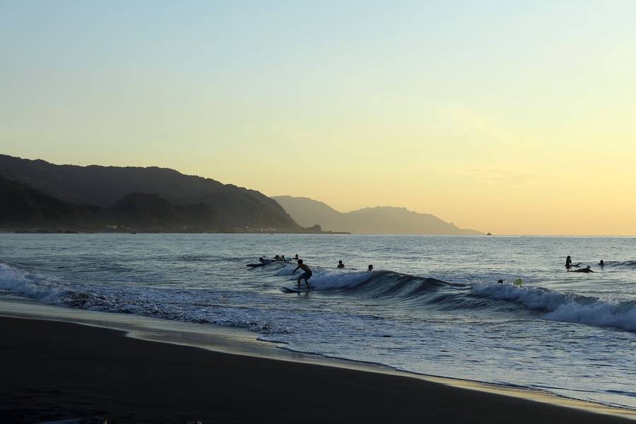 Du khách trải nghiệm lướt sóng tại bãi biển Waiao. 