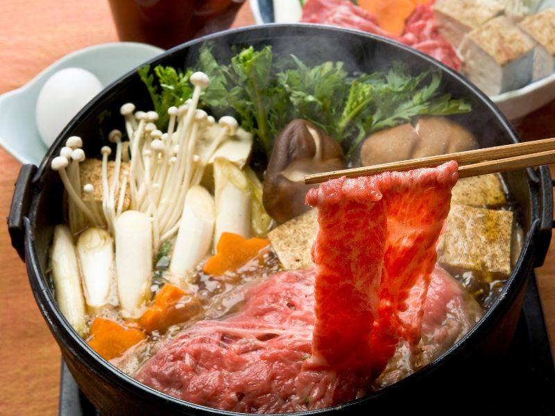 Nguyên liệu của sukiyaki quan trọng nhất là thịt bò, thường là wagyu hoặc bò Nhật, được thái lát mỏng để dễ thấm gia vị và chín nhanh trong nồi lẩu. Chất lượng thịt quyết định phần lớn trải nghiệm khi ăn sukiyaki, đặc biệt là độ mềm và vị ngọt tự nhiên.
