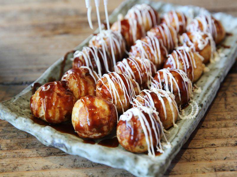 Sốt Takoyaki có vị mặn ngọt hài hòa, mayonnaise Nhật béo nhẹ, kết hợp cùng rong biển khô (aonori) và cá bào (katsuobushi). Khi bánh còn nóng, cá bào chuyển động nhẹ trên bề mặt, tạo nên hình ảnh rất đặc trưng của Takoyaki Nhật Bản.