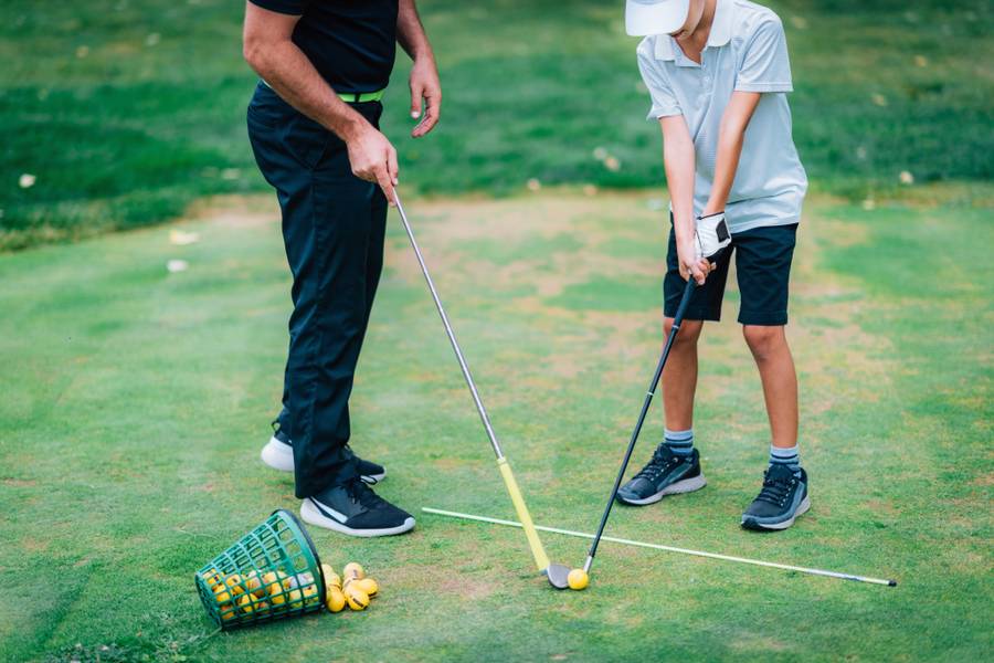 Golf personal training golf instructor teaching young boy how to play golf