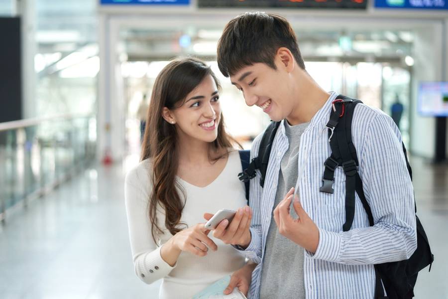  A young couple waiting for a train when they see their smartphones at a train station