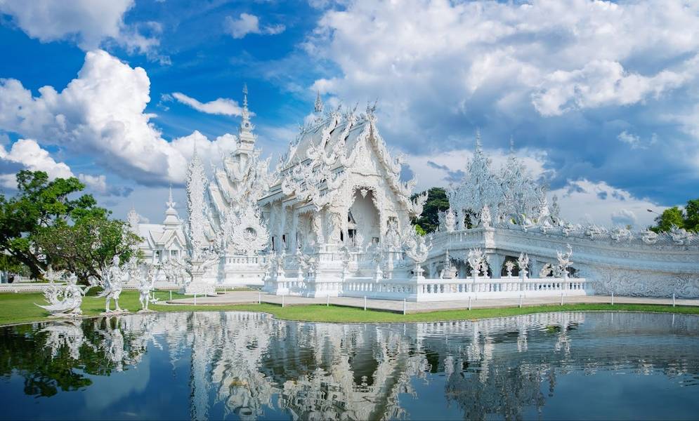 화려한 백색 건축미가 돋보이는 왓 롱 쿤의 전경과 맑은 하늘 아래 연못에 비치는 모습.
