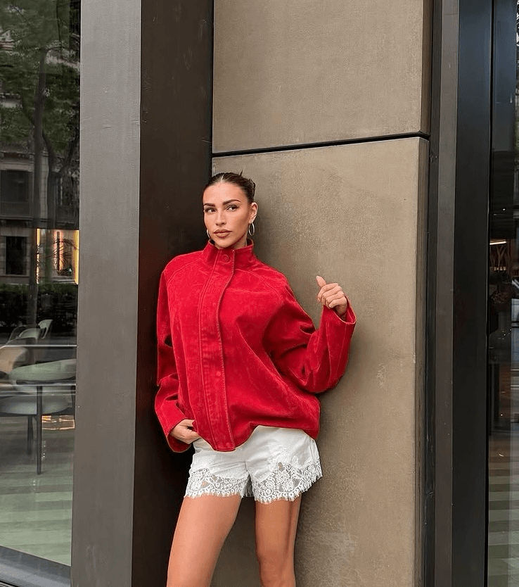 Zara McDermott wearing a red bomber jacket from Sisters and Seekers