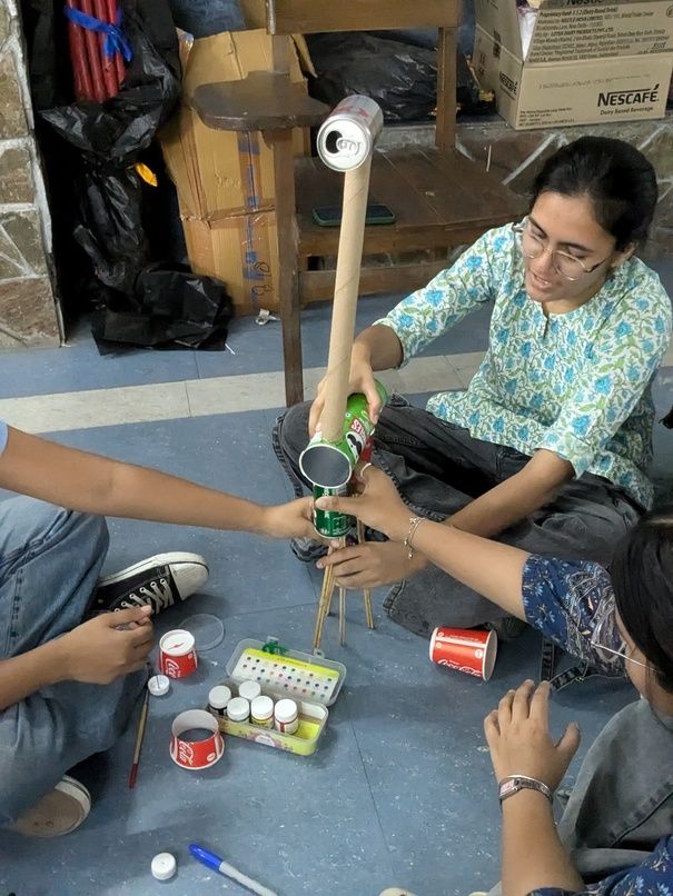 A giraffe getting built using cans and an empty roll