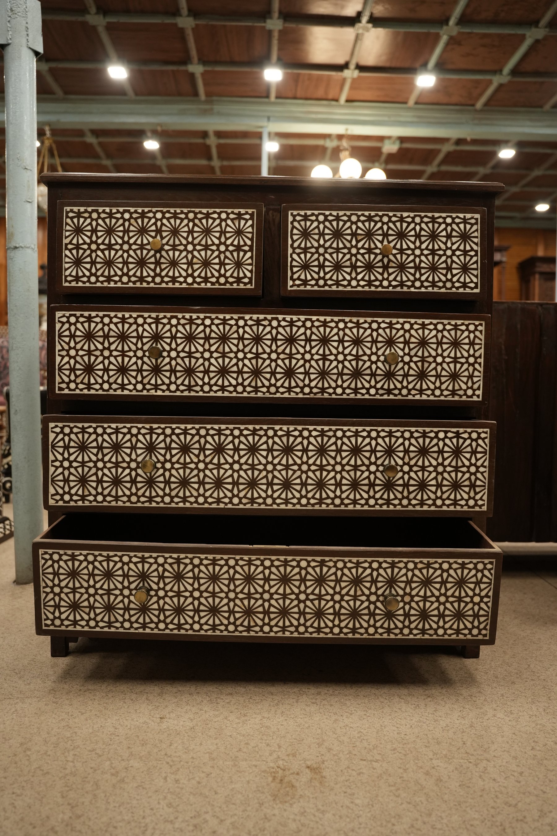 This chest of drawers features intricate, geometric mother of pearl inlay patterns set against a dark wood finish.