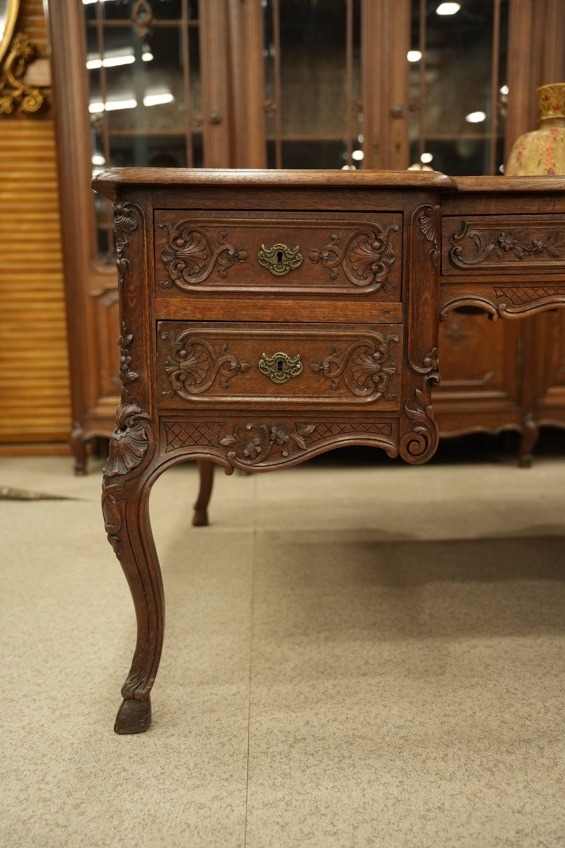 This antique French Louis XV style desk is crafted from solid oak and features intricate floral carvings and cabriole legs.