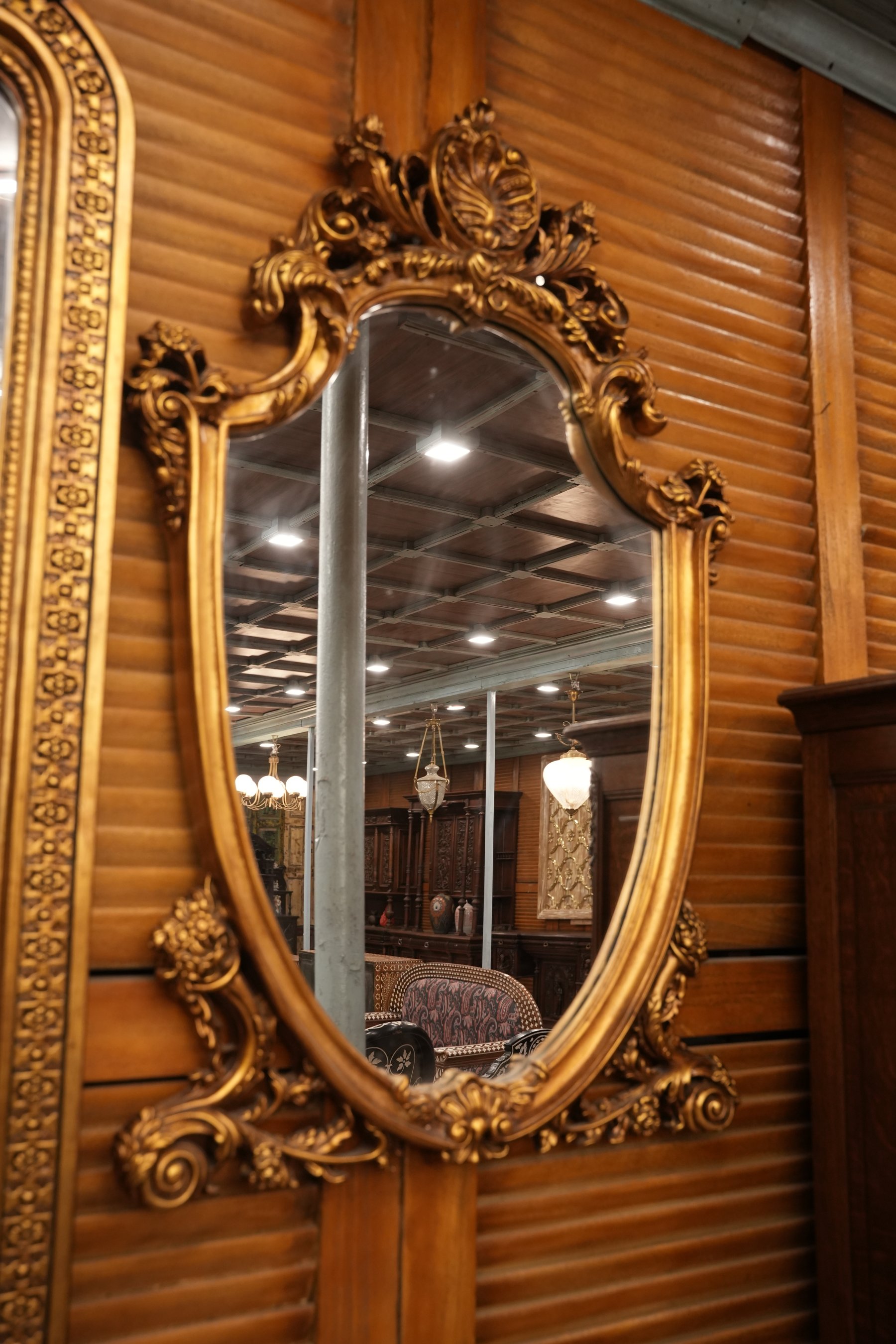 A grand arched wall mirror with carved golden detailing and a crown crest, blending timeless elegance with royal craftsmanship.