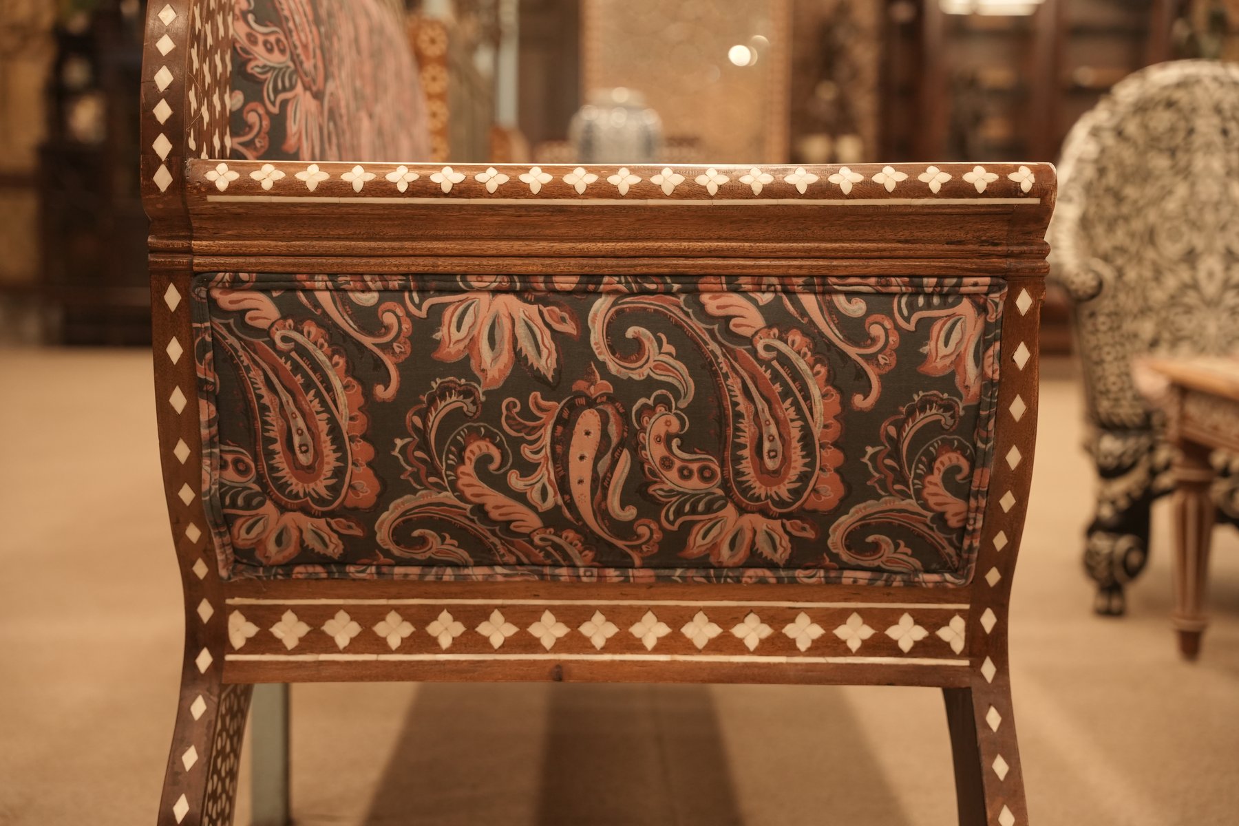 A handcrafted two-seater sofa with intricate mother-of-pearl inlay on a dark wood frame, blending traditional elegance with royal craftsmanship.