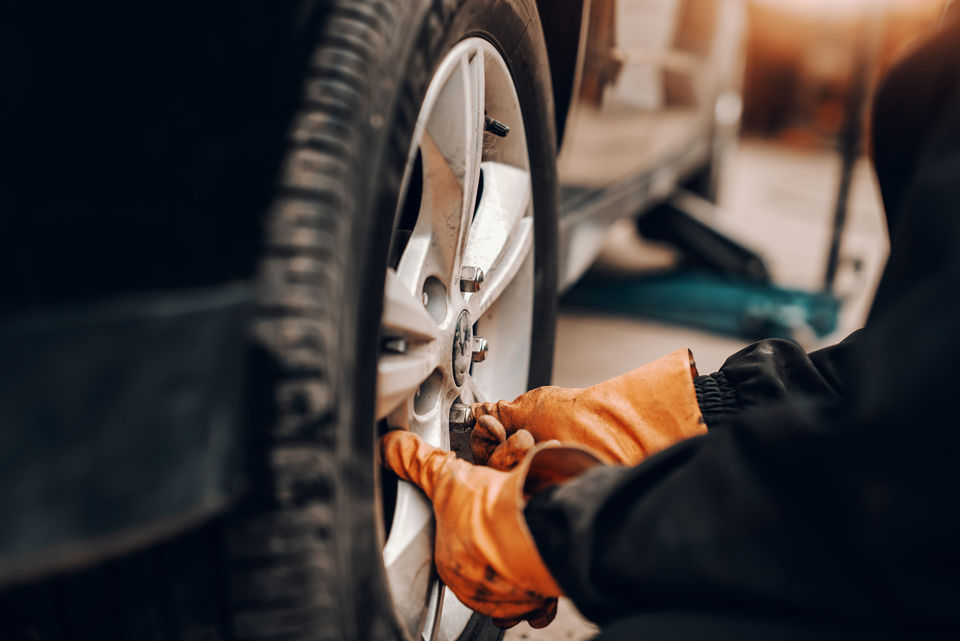 Skilled technician performing tyre rotation