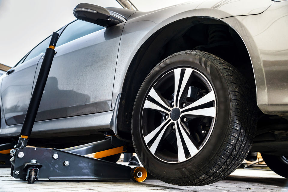 Car on a lift with a jack ready for wheel balancing and alignment