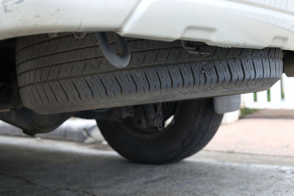 Spare tyre placed underneath a car highlighting a practical and space-saving feature