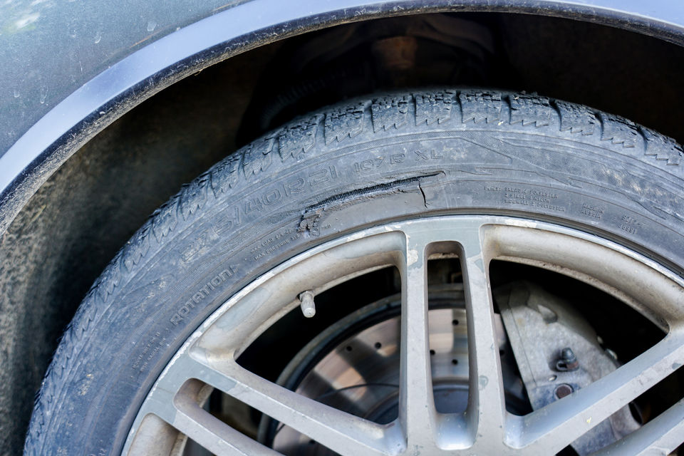 Tyre with a deep cut caused by curb collisions on the road