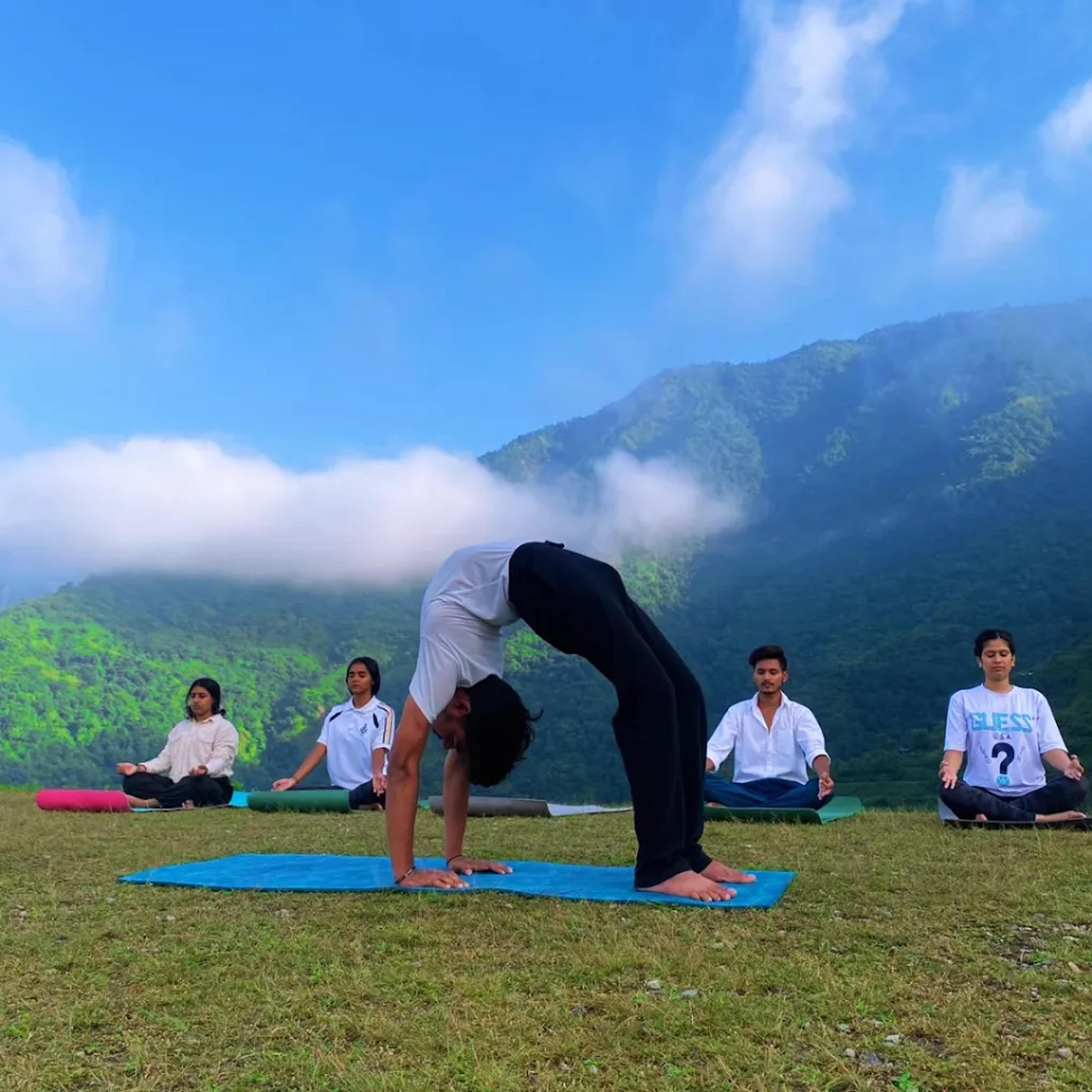 A group practising yoga on a terrace overlooking the Dehradun hills